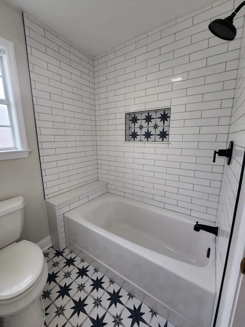 Bathroom with white subway tile tub surround, patterned floor tile, and matte black fixtures, a CoreBuild project