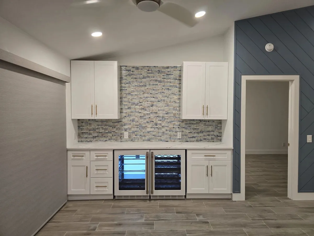 Beverage bar with white shaker cabinets, glass mosaic backsplash, and two under-counter fridges